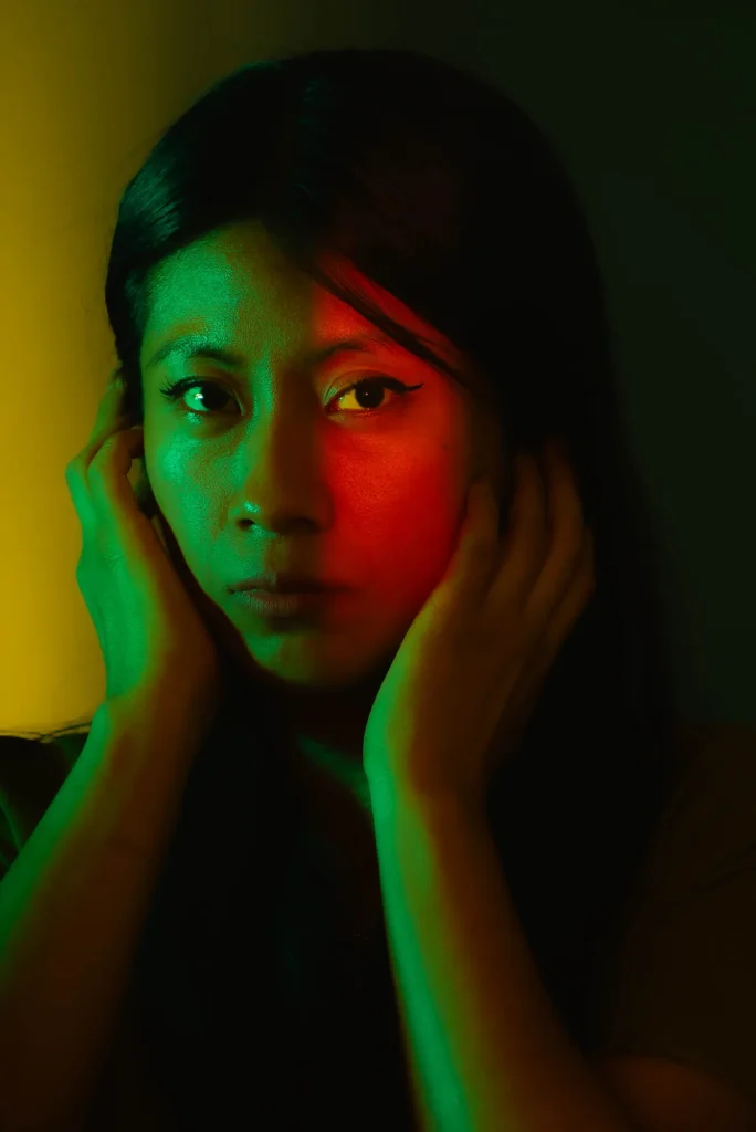 Green and red light, hands framing her face