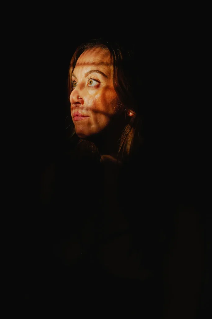 Shadows of the blinds across her face