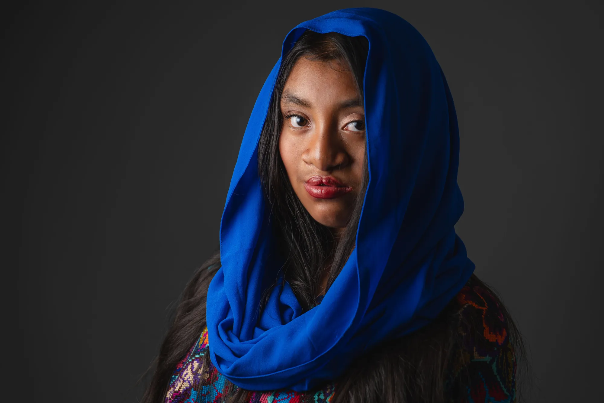 A blue shawl over an embroidered huipil