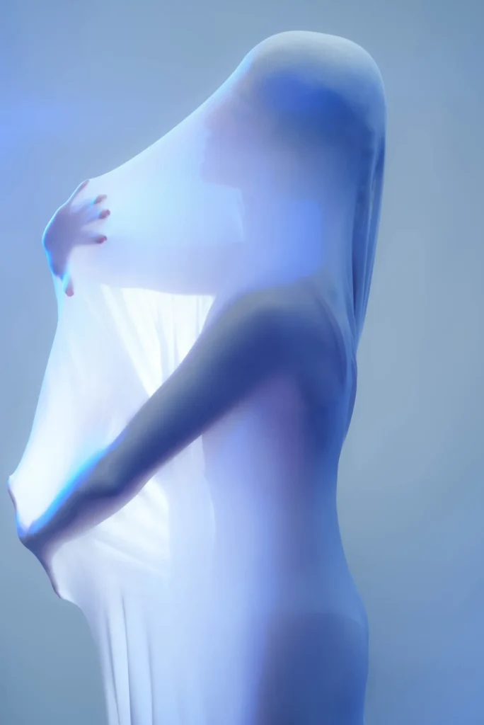 A figure behind white fabric, in blue light
