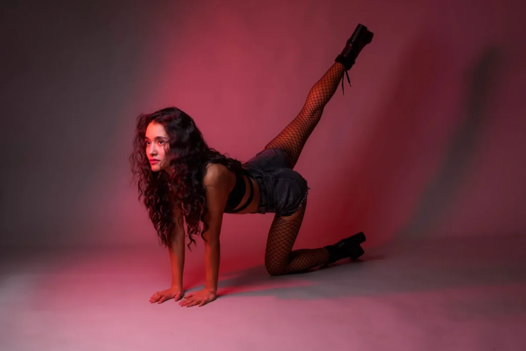 One leg kicked up, in red light