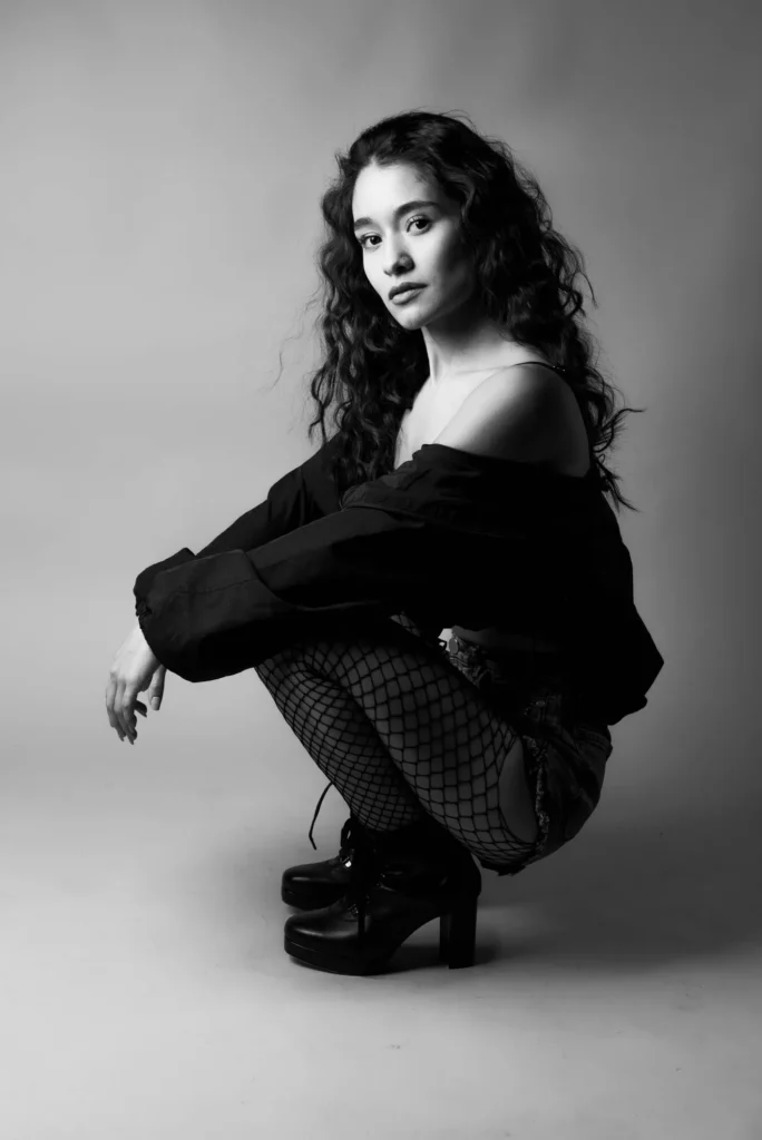 Crouched in fishnets, in black and white