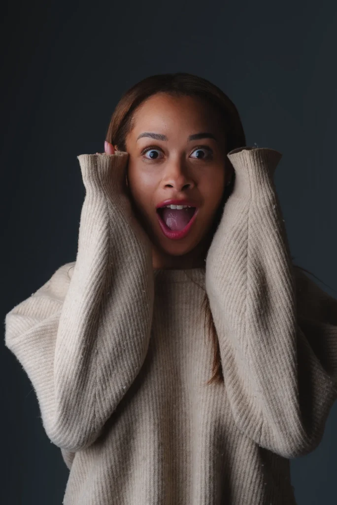 Hands on her cheeks, pure surprise