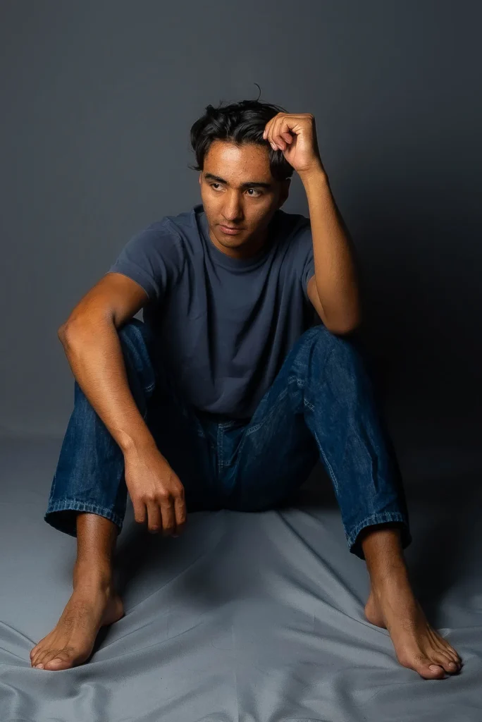 Seated barefoot, a hand in his hair