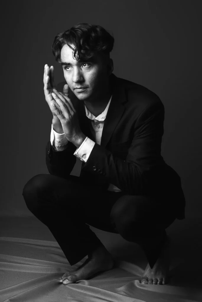 Crouched in a suit, barefoot, in black and white