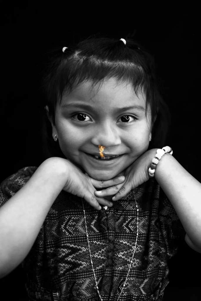 A girl rests her chin on her hands and smiles