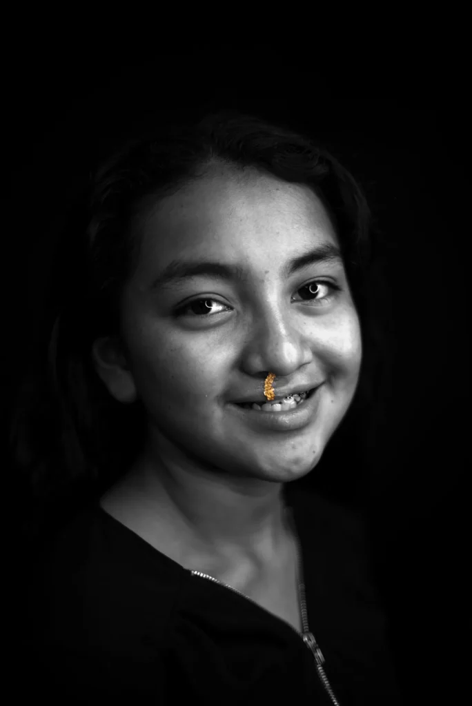 A teenager smiles, a gold line above her lip
