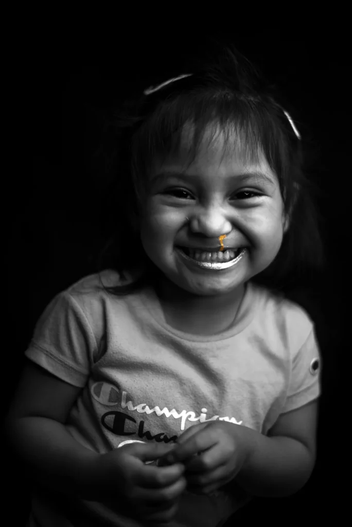 A little girl laughs with her eyes closed