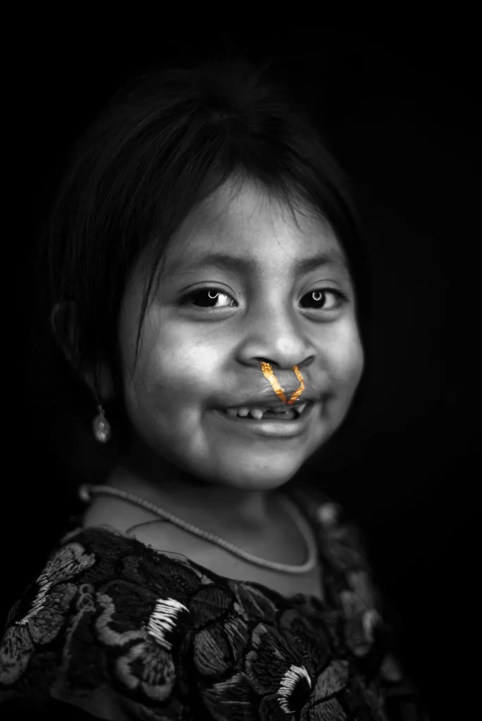 A girl in an embroidered blouse holds the camera's gaze