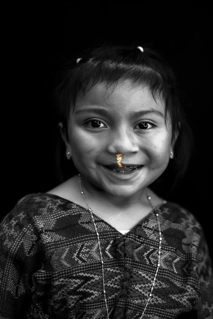 A girl in a woven blouse smiles at the camera