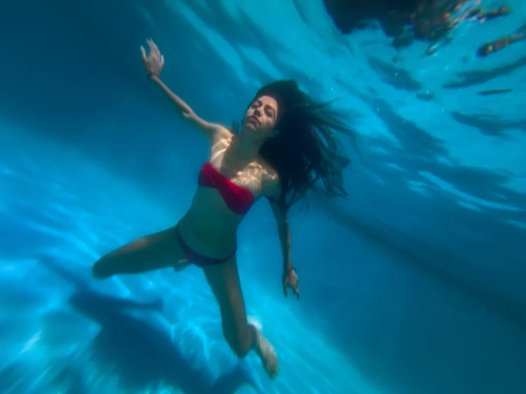 Floating in blue water, arms open