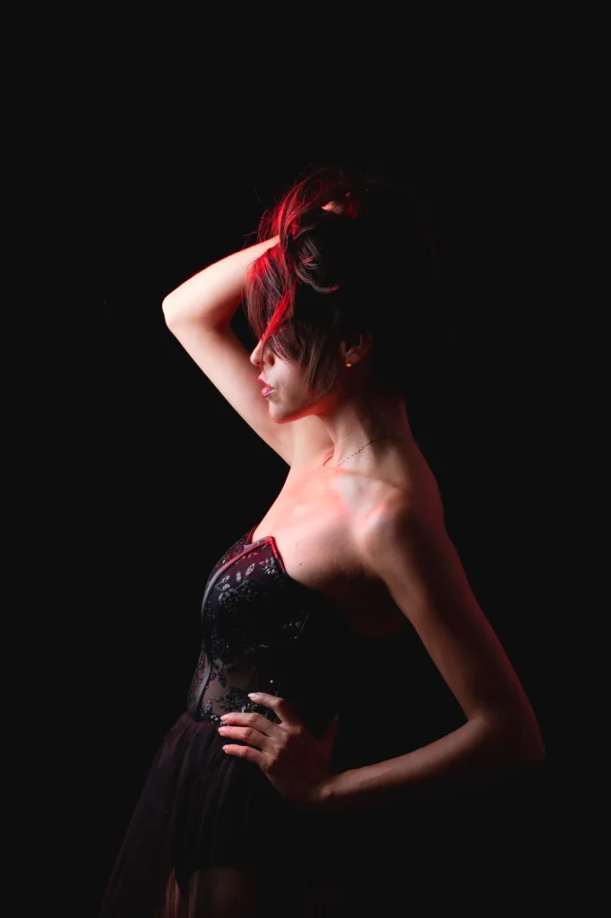 Red light on her hair, a hand on her hip