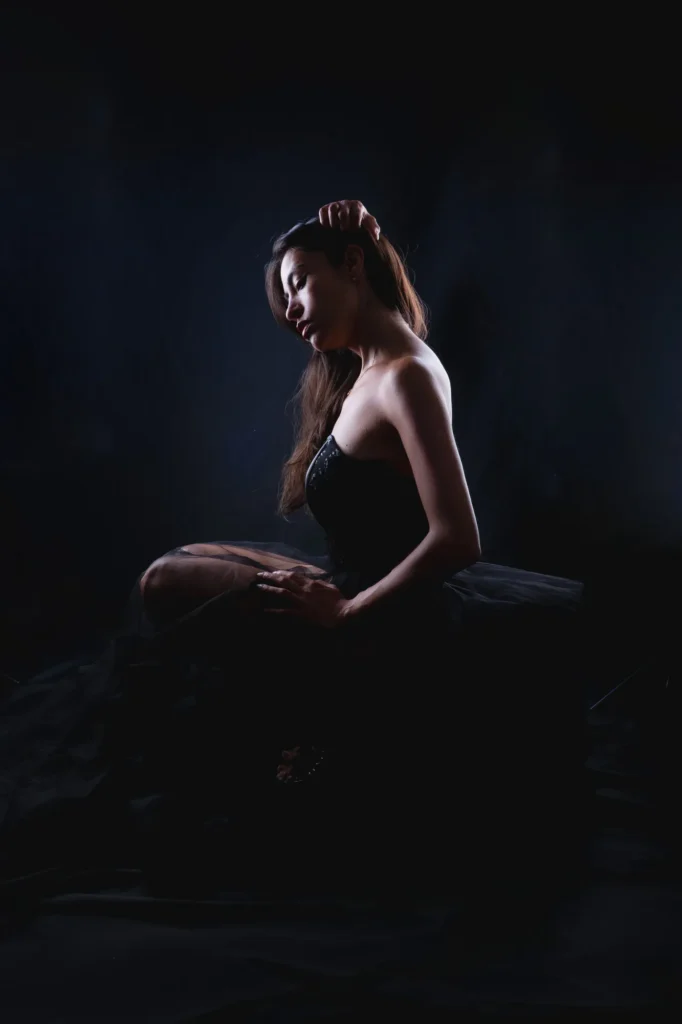 Seated in the dark, head bowed