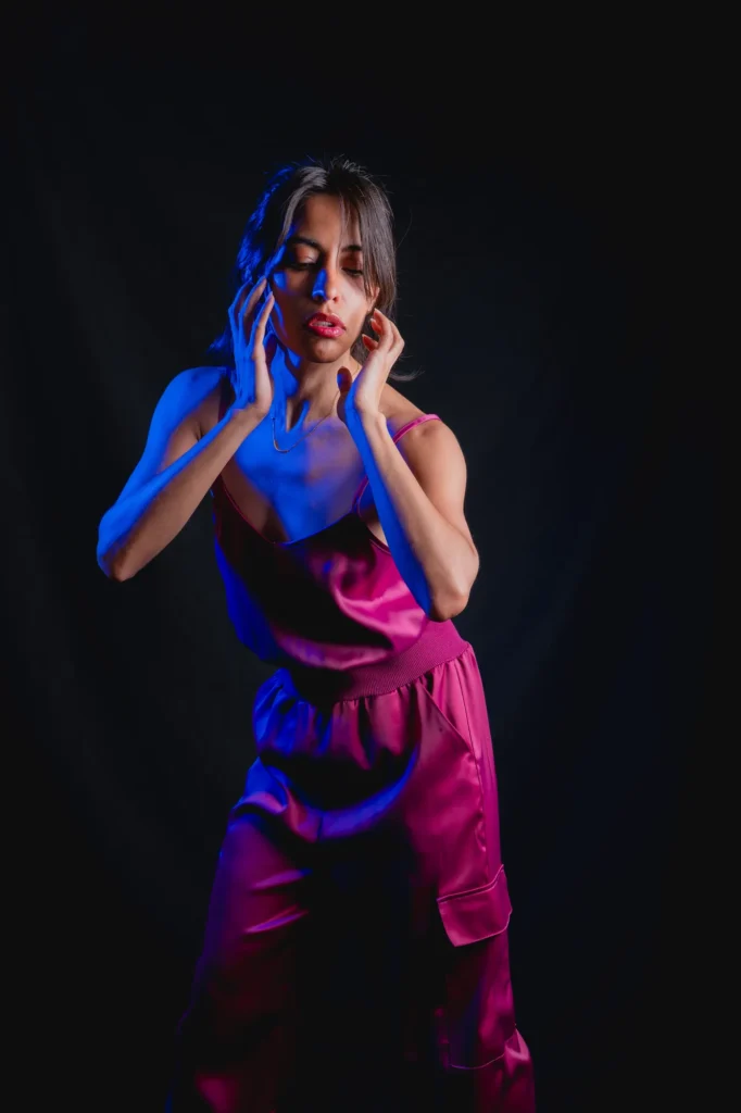 Hands at her face in pink and blue light
