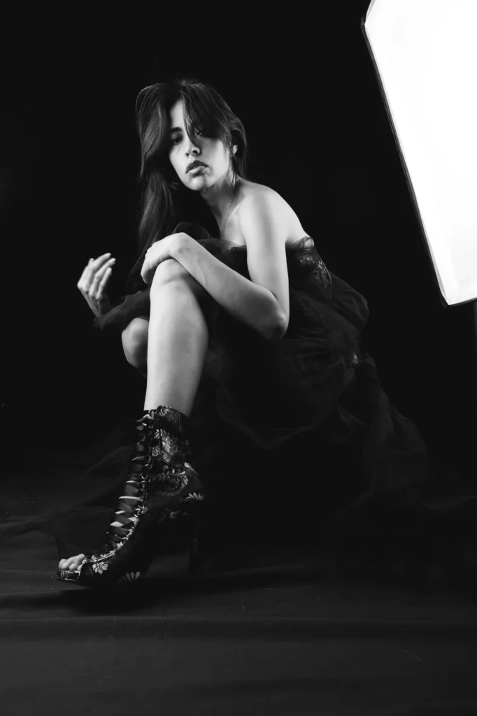 Seated with a knee raised, in black and white