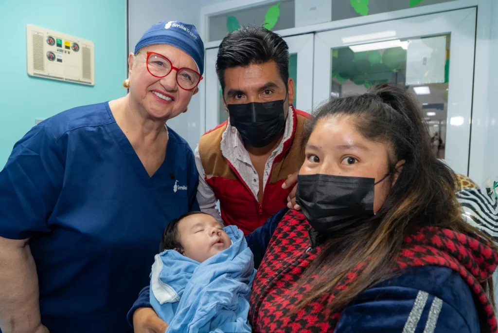 Lidia in scrubs with a family and their newborn