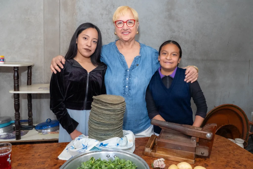 Lidia with two young women by a stack of tortillas