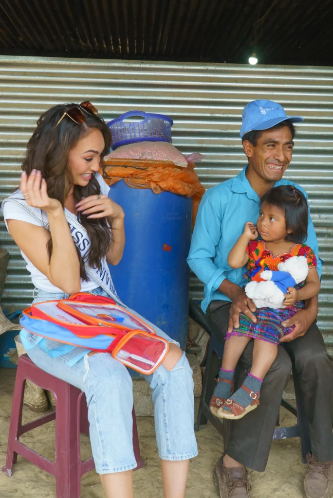 A titleholder with a father and his child outside their home