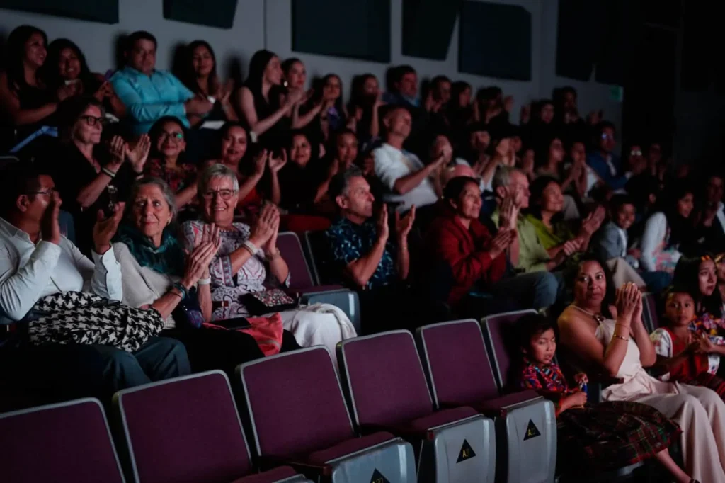 The audience applauds from the seats